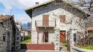 A stone building with a metal gate, wooden shutters, and a stone wall.