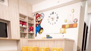 A room with a Mario-themed welcome mat, a clock on the wall, and a shelf with various items. - BAOBAOB&B (Magong)