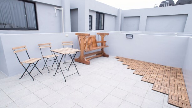 A rooftop terrace with a seating area, including a wooden bench and chairs, and a small table. - BAOBAOB&B (Magong)