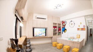 A modern kitchen with a TV, coffee machine, bar stools, and a Mario-themed wall decoration. - BAOBAOB&B (Magong)