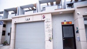 A building with a large garage door, a black entrance gate, and a sign with Chinese characters. - BAOBAOB&B (Magong)
