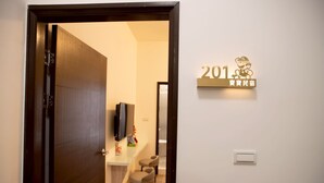 A hotel entrance with a wooden door, a reception desk, a TV, and a wall sign with the number 201. - BAOBAOB&B (Magong)