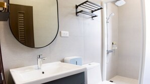 A modern bathroom with a vanity, sink, mirror, toilet, and shower. - BAOBAOB&B (Magong)