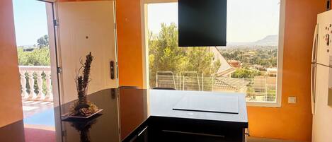 A kitchen with a view of a cityscape, a white refrigerator, and a black countertop.