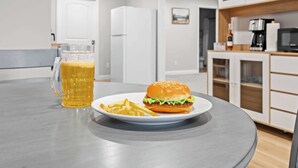 Ein Esstisch mit einem Teller Essen, einem Bierglas und einem Sandwich.