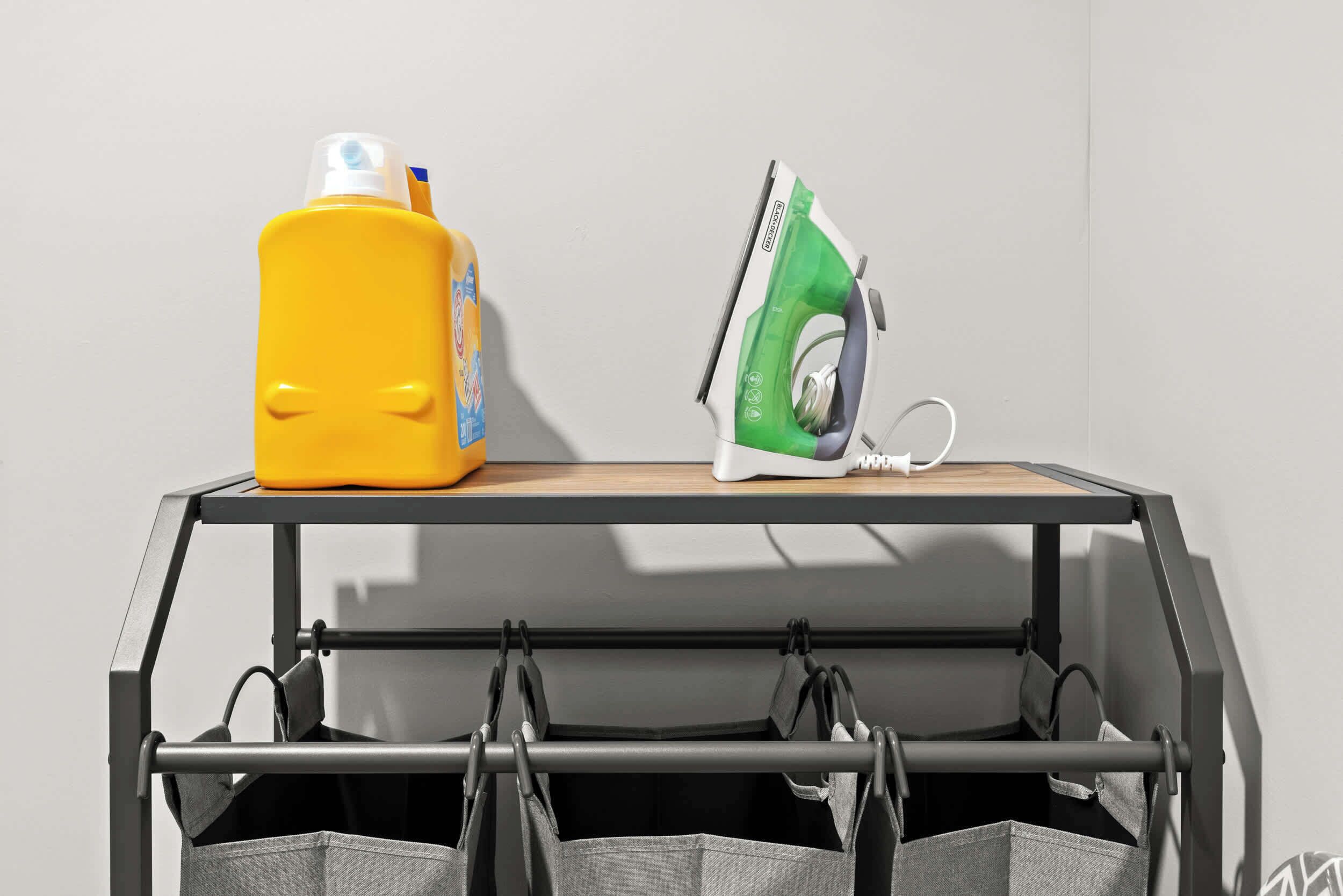 A metal table with a bottle of yellow detergent and an iron on top.