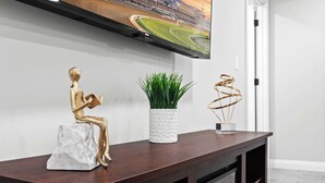 Ein Holzkonsolentisch mit einer goldfarbenen Statue, einer weißen Vase mit Grünpflanzen und einer goldfarbenen Spiralplastik.
