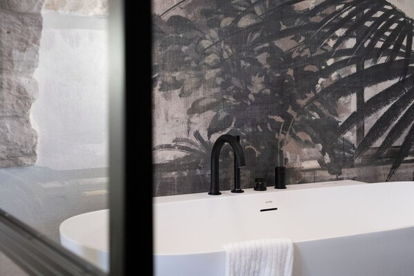 A modern bathroom with a white bathtub, black faucets, and a towel hanging on the side. - Trullo delle Sfere, a luxury trullo in the center of Alberobello (Alberobello)