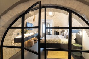 A bedroom with a bed, bedside tables, and a view through a window. - Trullo delle Sfere, a luxury trullo in the center of Alberobello (Alberobello)