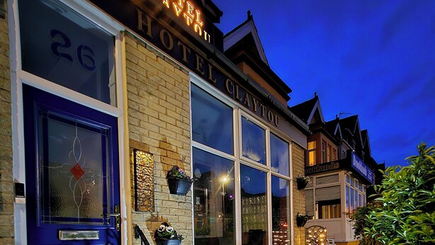 A hotel with a prominent sign, a blue door, and a staircase leading to the entrance.