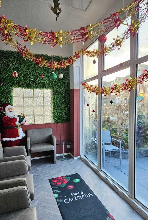 A room with a Christmas theme, including a Santa Claus figure, festive garlands, and a 'Merry Christmas' mat. - Hotel Claytou (Blackpool)