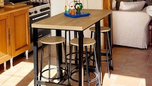 A kitchen with a wooden table, bar stools, a chandelier, and a window with a view. - TBM gîte country house completely renovated and quiet (Clamerey)