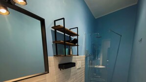 A bathroom with a white sink, a bidet, and a toilet. There is a mirror above the sink, and a shelf with a black frame on the wall. The floor has a patterned tile design. - Caramia srls (Crispiano)
