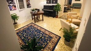 A living room with a piano, a dining table, and a blue patterned rug. - Caramia srls (Crispiano)