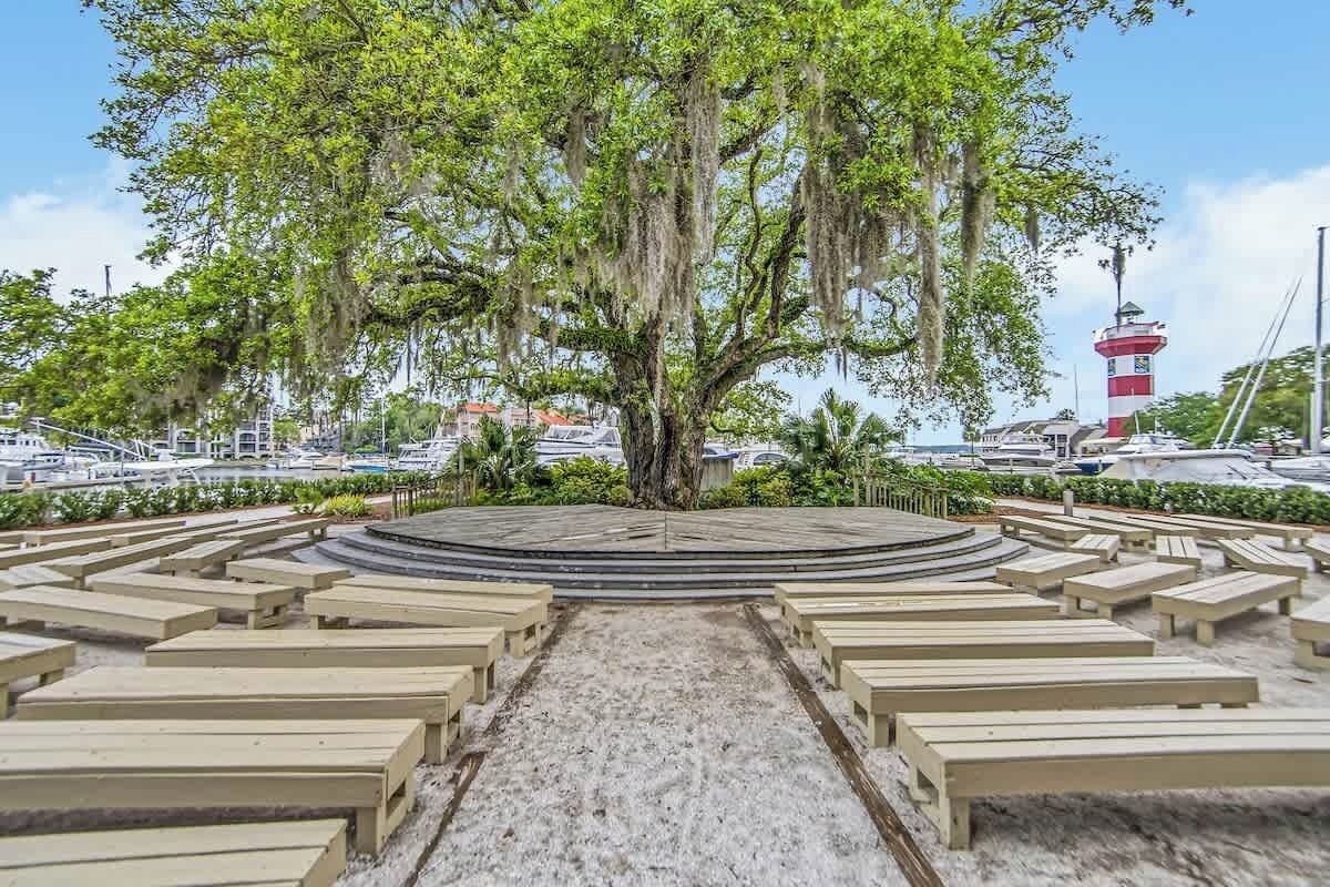 A circular outdoor seating area with benches arranged around a central tree.