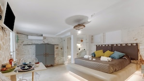 Un dormitorio moderno con una cama grande, una mesa de comedor con sillas y un televisor montado en la pared.