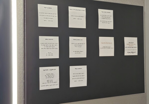 A bulletin board with various signs in Korean, indicating different hotel services such as lounge, reception, check-out, theater, and laundry.