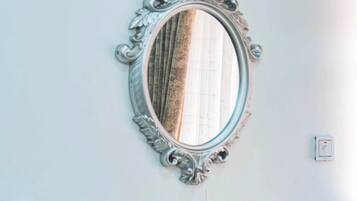 A mirror with an ornate frame, a gold statue, a white bottle, and a light switch on the wall.