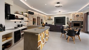 Una cocina moderna con una isla central, electrodomésticos integrados y una pared decorativa de piedra.