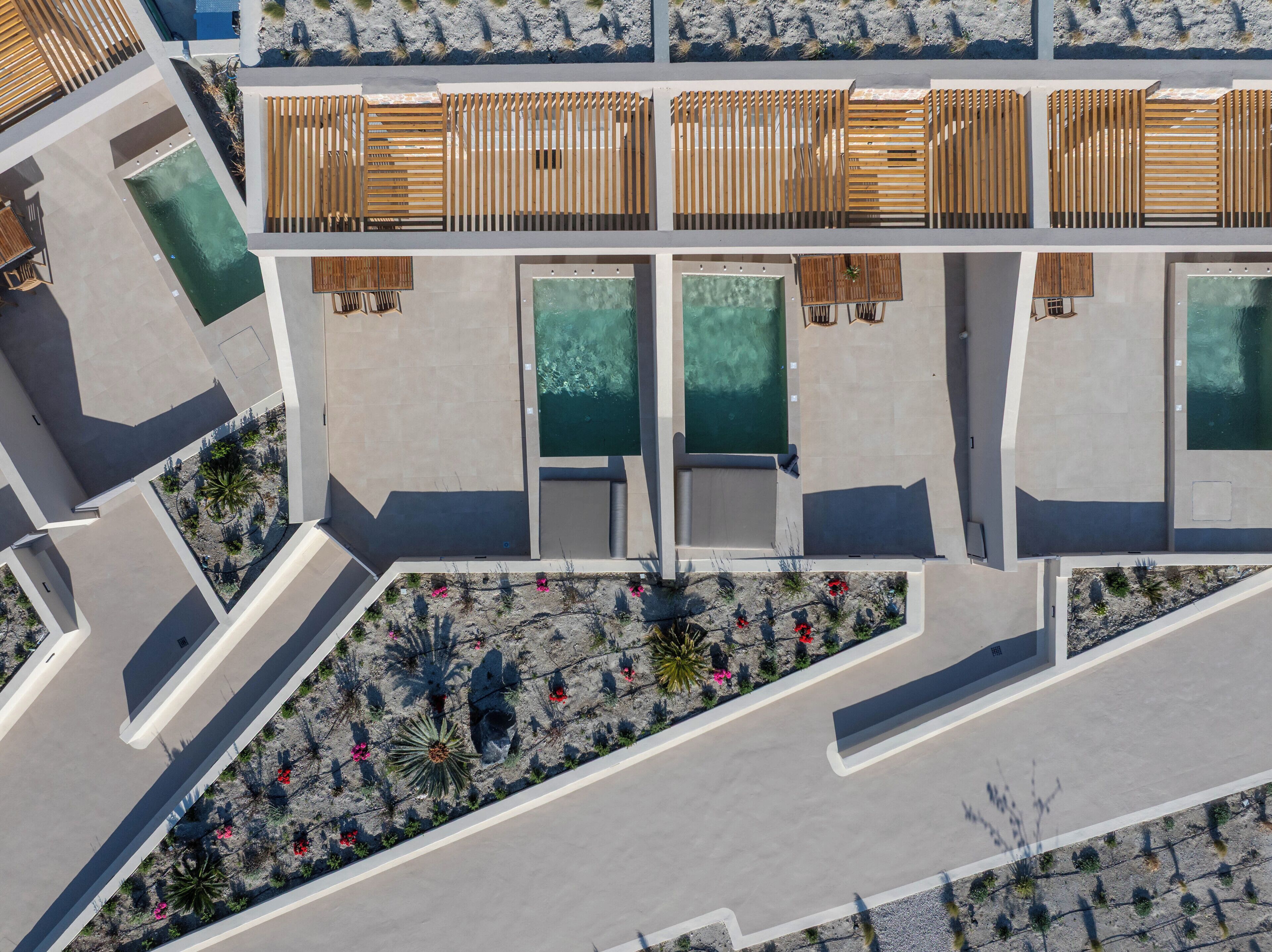 Vista aérea de un resort con múltiples piscinas, zonas de terraza de madera y jardines ajardinados.
