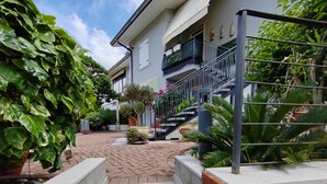 A residential building with a brick staircase leading to a balcony, surrounded by potted plants and a clear sky. - Charming 4-bedroom estate in enchanting Albaré Stazione with AC, WiFi (Albaré Stazione)