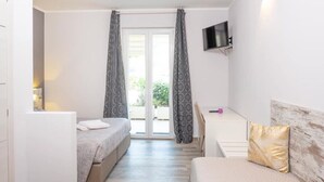 A bedroom with two beds, a desk, a television, and a sliding glass door to the outside. - Charming 4-bedroom estate in enchanting Albaré Stazione with AC, WiFi (Albaré Stazione)