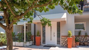 A modern building with a white facade, a glass door entrance, and potted plants. - Charming 4-bedroom estate in enchanting Albaré Stazione with AC, WiFi (Albaré Stazione)
