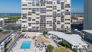 A multi-story hotel with a pool area, outdoor seating, and a view of the ocean. - Perfect beach getaway at Fountainhead Towers, located oceanfront on 116th Street (Ocean City)