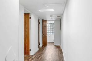 Un pasillo con puertas de madera, paredes blancas y suelo de madera.