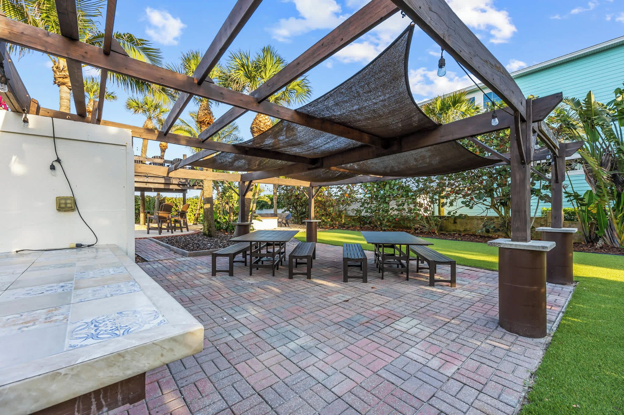 Shaded outdoor seating area with picnic tables and tropical landscaping for relaxing gatherings.