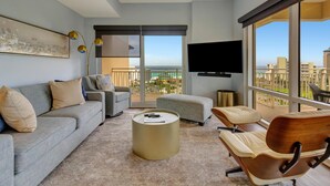 A modern living room with a gray sofa, a wooden chair, a round coffee table, and a TV mounted on the wall. - 1BR 8th Floor Luau, spanning views of a lagoon pool and the Gulf at Sandestin Golf & Beach Resort (Miramar Beach)