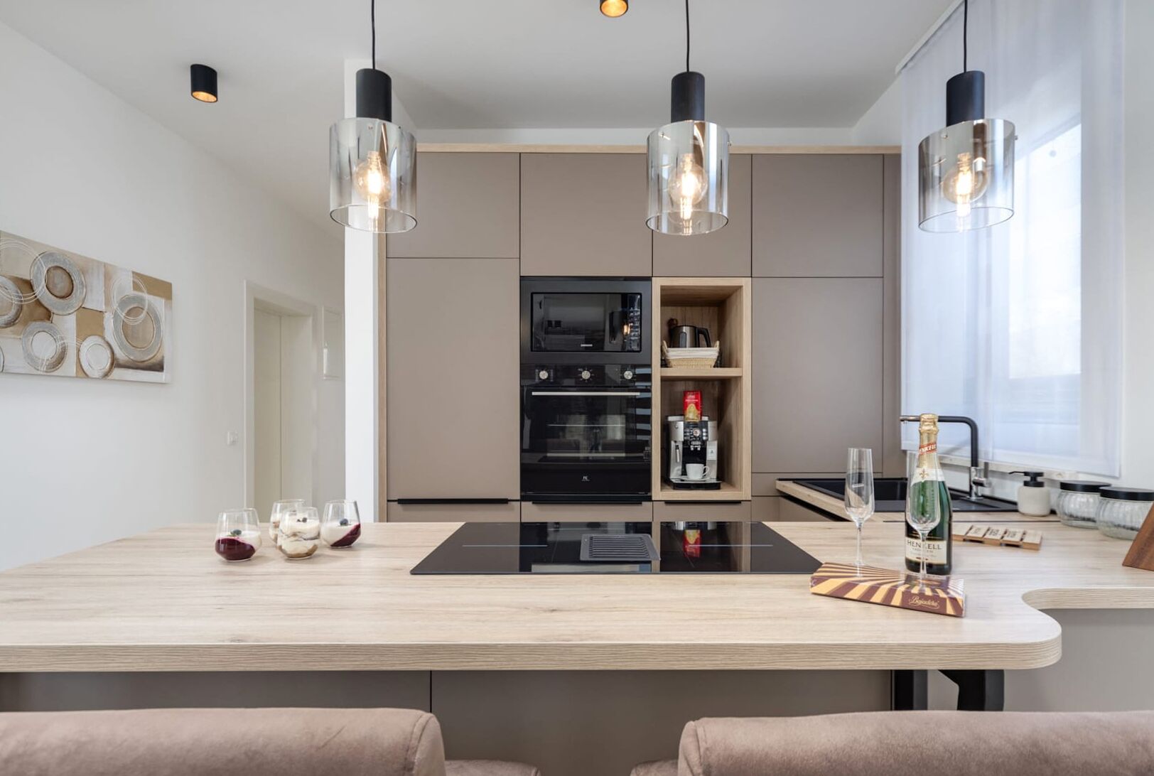 A modern kitchen with a central island, built-in appliances, and pendant lighting.