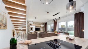 A modern kitchen with a central island, built-in appliances, and a dining area with a view. - Villa Sanja Zadarvillas (Nin)
