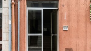 A building entrance with a glass door and a brick wall. - Lovely Terrace Apartment by Wonderful Italy (Bari)