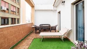 A small outdoor patio with a table and chairs, a small patch of artificial grass, and a brick floor. - Lovely Terrace Apartment by Wonderful Italy (Bari)