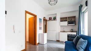 A compact living space with a kitchenette, a blue sofa, and a tiled floor. - Lovely Terrace Apartment by Wonderful Italy (Bari)