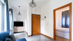 A modern living room with a sofa, a TV, and a wooden door leading to a bedroom. - Lovely Terrace Apartment by Wonderful Italy (Bari)