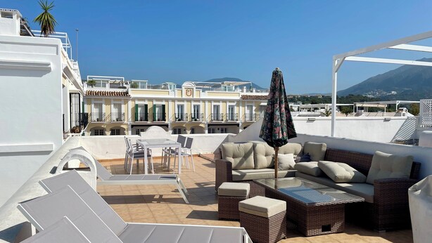 Una terrazza panoramica con arredi da esterno, tra cui divano, poltrone e un tavolo.