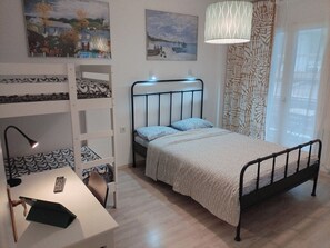 A bedroom with a bunk bed, a desk with a lamp, and a bed with patterned bedding. - Center Apartment-sleeps5-balcony-live Neighborhood (Thessaloniki)