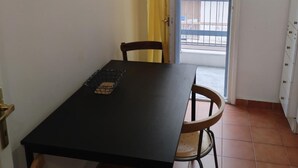 A dining table with chairs, a basket, and a door leading to a balcony.