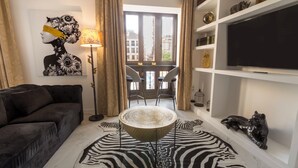 Un salon moderne comprenant un canapé, une table ronde, un tapis à motifs zébrés, un téléviseur et une bibliothèque.