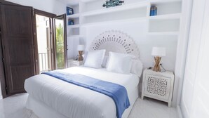 Une chambre à coucher avec un grand lit, des murs blancs et une porte en bois.