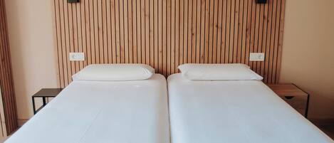 A room with two beds, wooden panel walls, and a wooden floor.