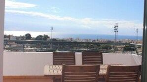 A balcony with a table and chairs, overlooking a cityscape and the sea. - MANGATA APARTMENT IN NERJA (Nerja)