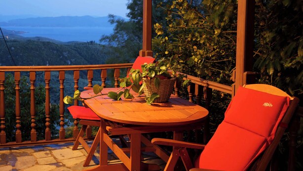 A wooden deck with a round table and two red chairs, overlooking a scenic view of hills and a body of water. - Stay Horizon #P1, Milies (Pelio)