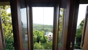 A room with a large sliding glass door leading to a scenic view of a mountainous landscape and a house. - Stay Horizon #P1, Milies (Pelio)