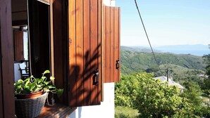 A wooden balcony with a potted plant, a view of a mountainous landscape, and a clear sky. - Stay Horizon #P1, Milies (Pelio)