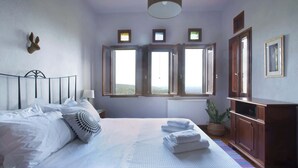 A bedroom with a bed, bedside tables, a lamp, a dresser, and a view through open windows. - Stay Horizon #P1, Milies (Pelio)