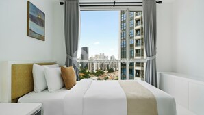Ein Hotelzimmer mit einem Bett, einem Schreibtisch und einem großen Fenster mit Vorhängen.
