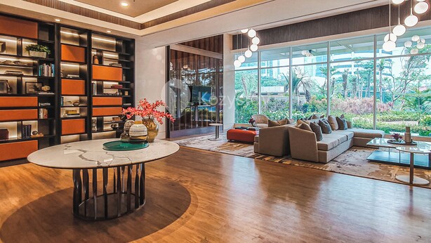 Een moderne woonkamer met een grote boekenkast, een ronde salontafel en een bank tegenover grote ramen.